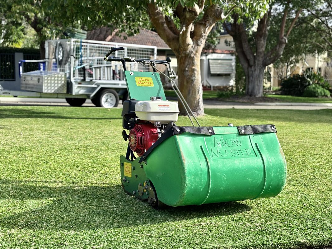 Professional garden maintenance team using specialised cylinder mower equipment on Perth lawn